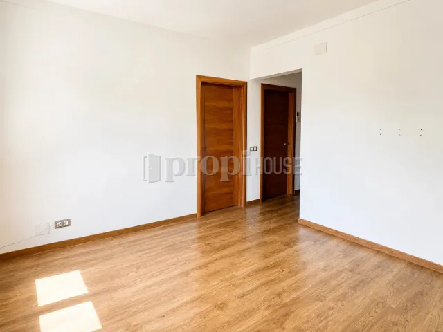 Salón con suelo de madera y salida al pasillo