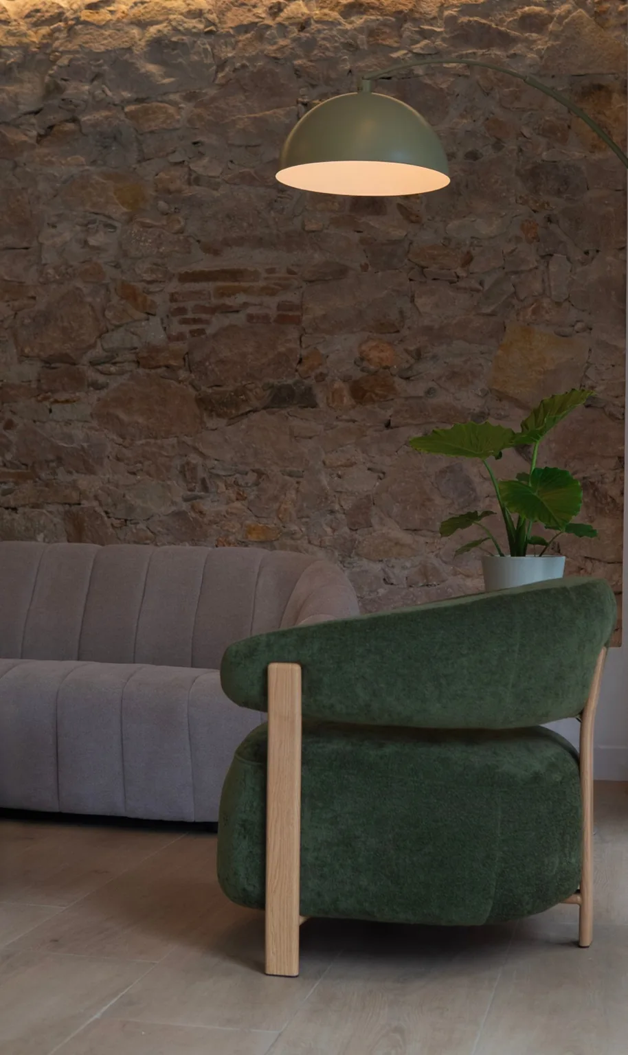 Oficina de Propi House en Sant Josep, L'Hospitalet: rincón de butacas sobre pared de piedra