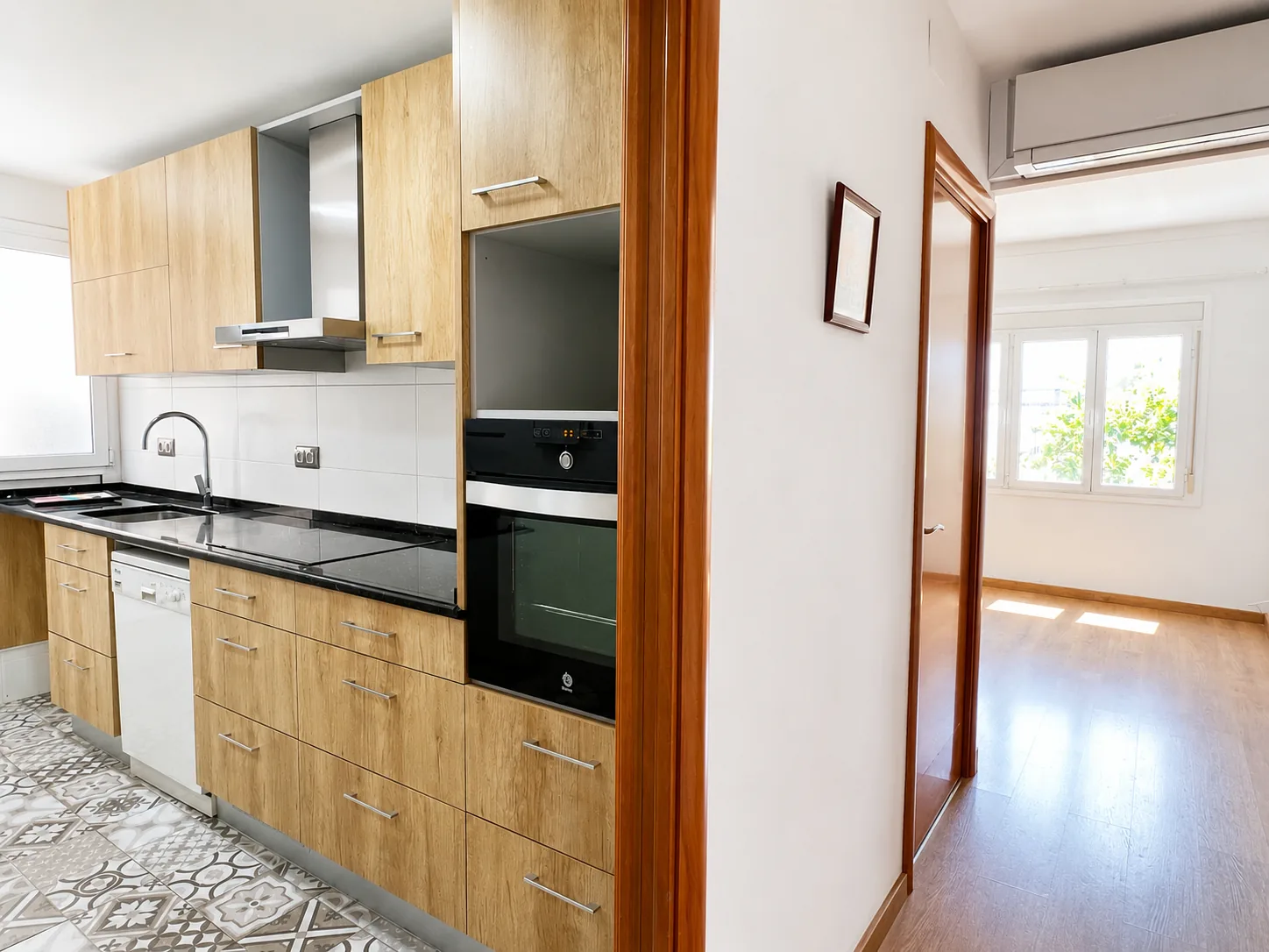Cocina con horno y lavavajillas, y el paso hacia el resto de la vivienda