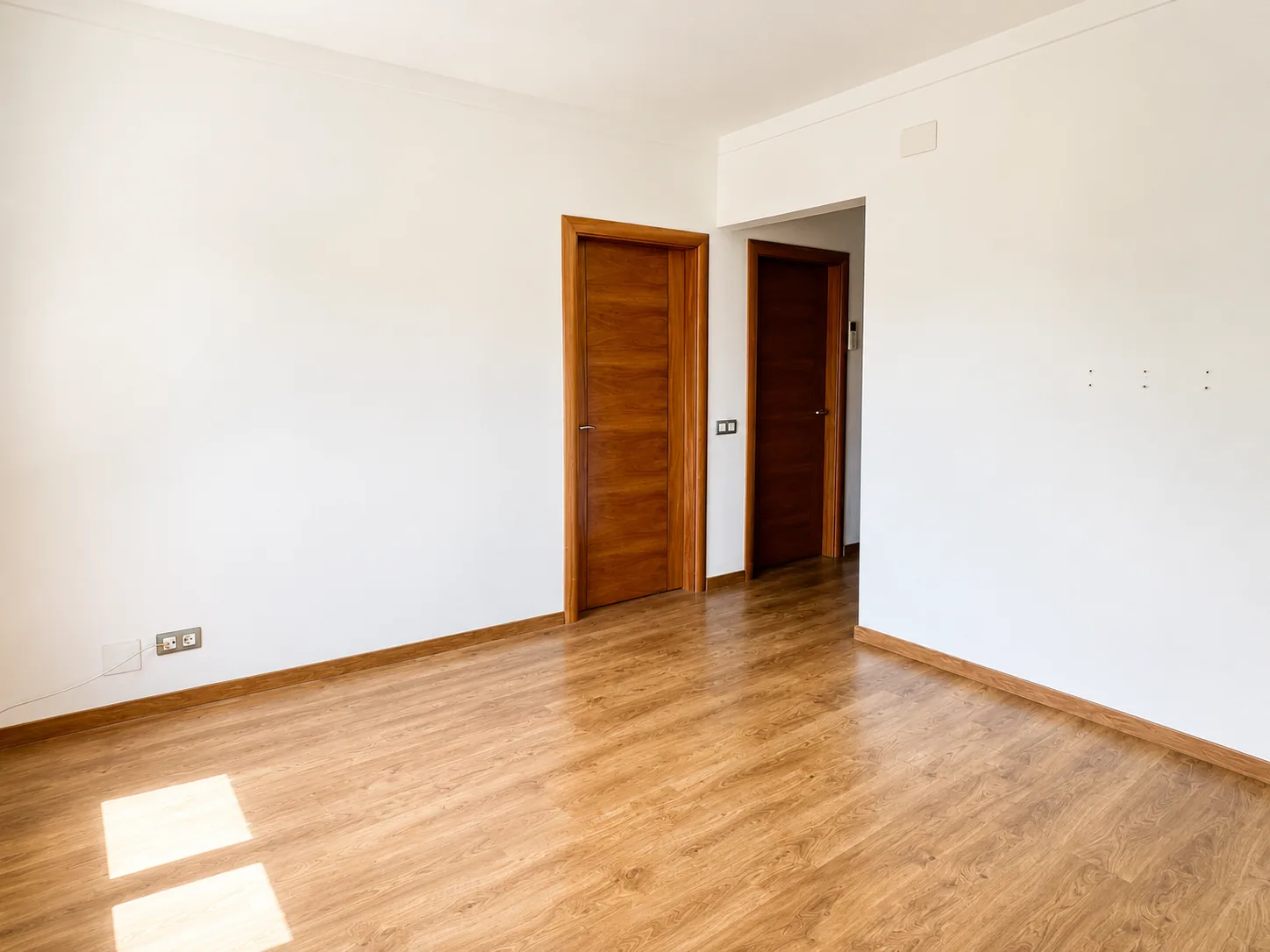 Salón con suelo de madera y salida al pasillo