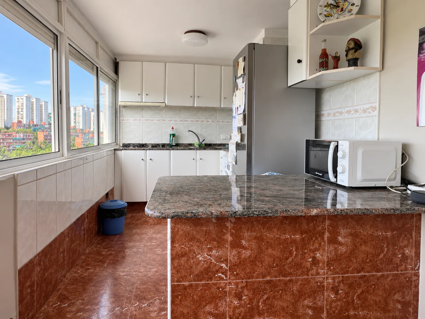 Cocina exterior con encimera de granito, muebles blancos y ventana panorámica