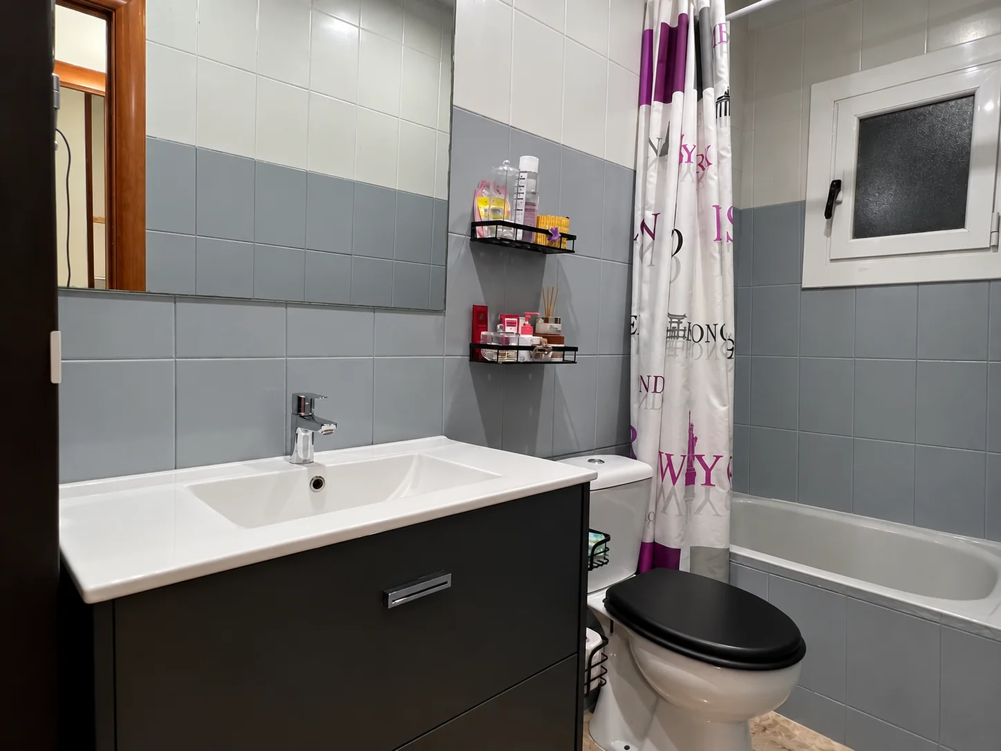 El baño entero: mueble de lavabo, bañera y ventana