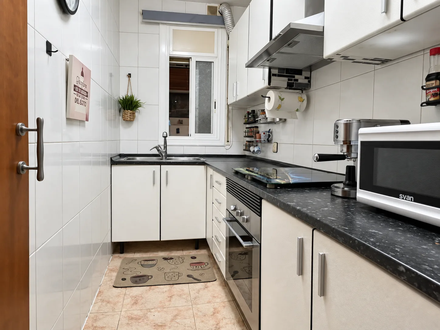 Cocina independiente con encimera de granito, muebles blancos y ventana