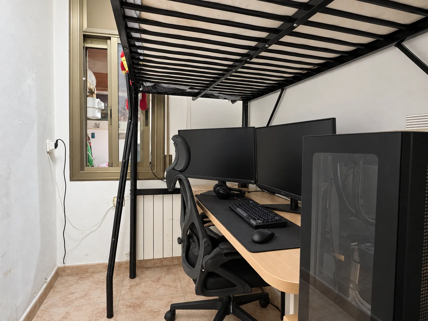 El escritorio bajo la cama alta, junto a la ventana