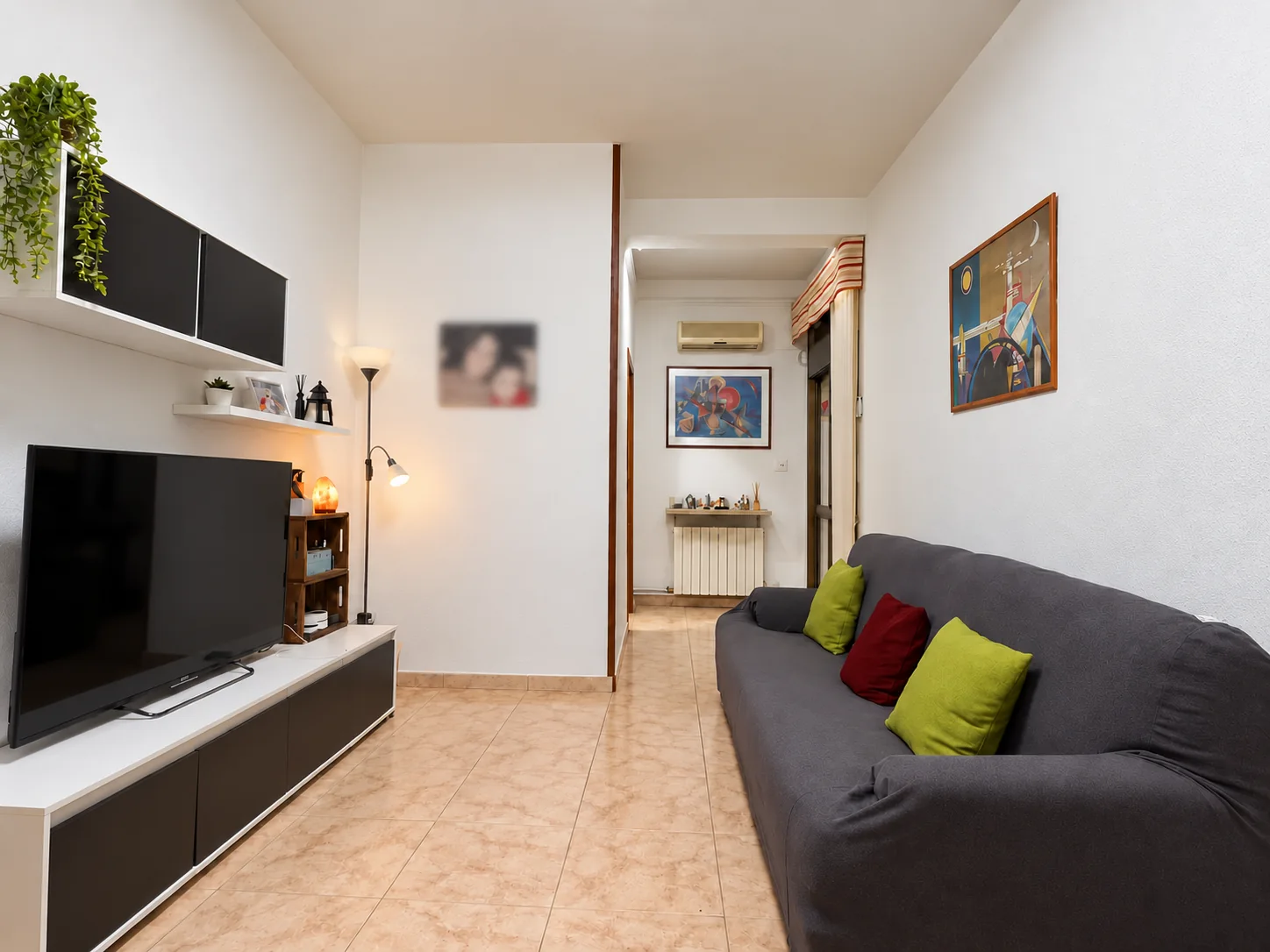 Salón con sofá, mueble de televisión y paso al distribuidor